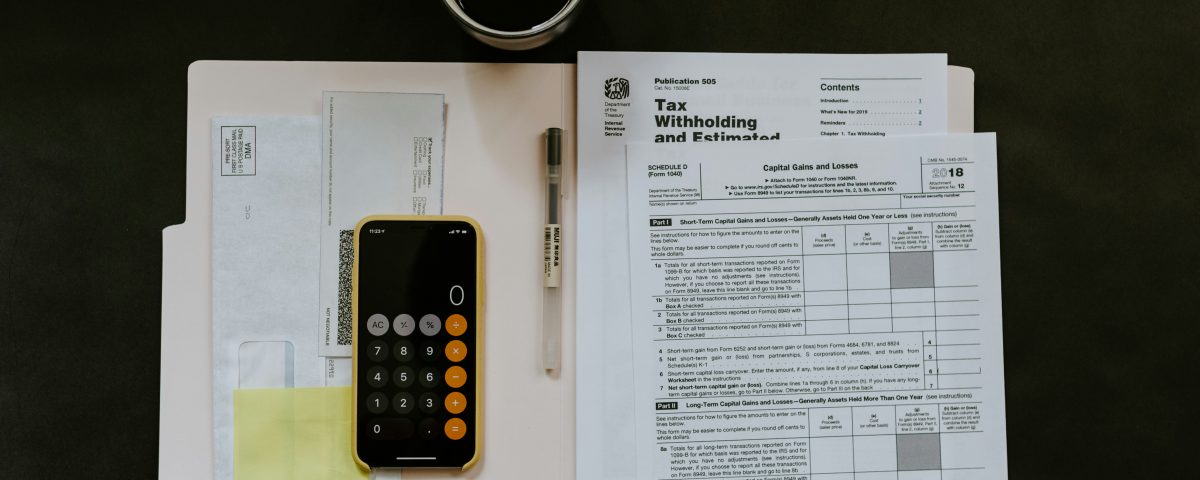 Tax forms, calculator, and phone on a desk representing vendor management and tax compliance for Colorado businesses