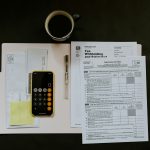 Tax forms, calculator, and phone on a desk representing vendor management and tax compliance for Colorado businesses