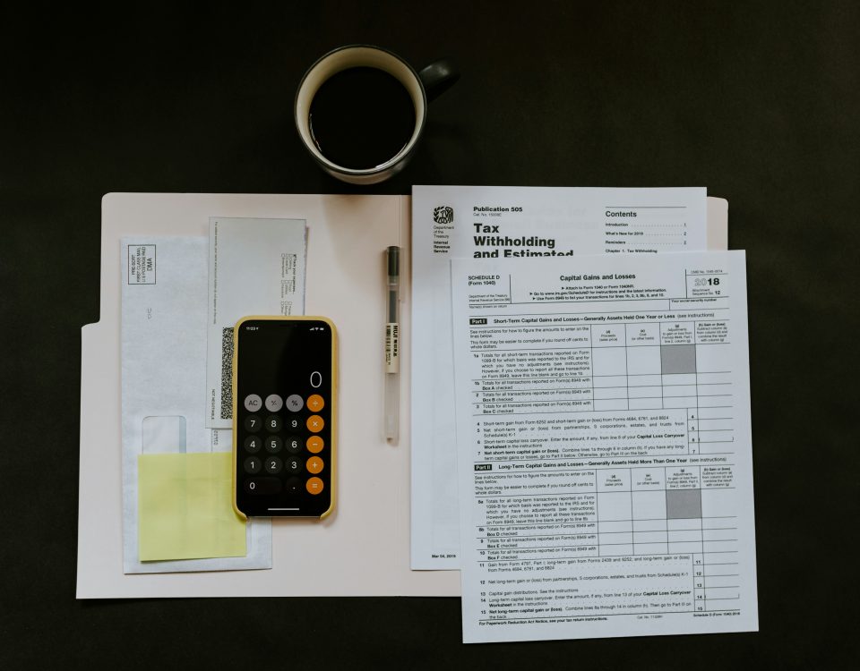 Tax forms, calculator, and phone on a desk representing vendor management and tax compliance for Colorado businesses